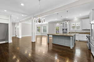Kitchen with open floor plan, a center island with sink, stainless steel appliances, white cabinets, and a breakfast bar