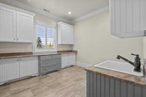 Laundry area with a sink, baseboards, ornamental molding, and recessed lighting