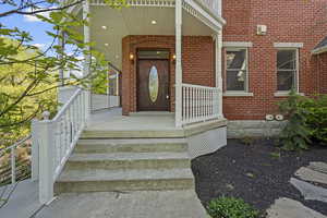 Entrance to property with brick siding and a porch