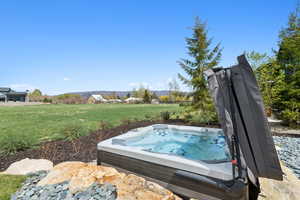 View of grassy yard featuring a hot tub and a mountain view