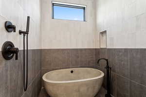 Full bathroom featuring tile walls, a freestanding bath, and a tile shower