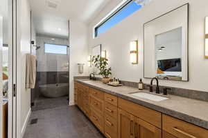 Ensuite bathroom with a stall shower, double vanity, a freestanding tub, baseboards, and tile patterned floors