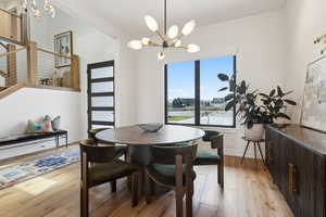 Dining area with a chandelier, light wood-type flooring, baseboards, and stairs