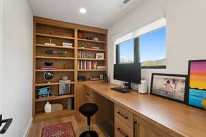Office space featuring wood finished floors, built in desk, and recessed lighting