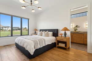 Bedroom with light wood-type flooring, a chandelier, and baseboards