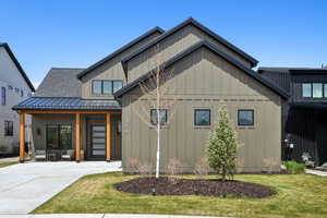 Modern inspired farmhouse featuring board and batten siding, a front yard, metal roof, and a standing seam roof