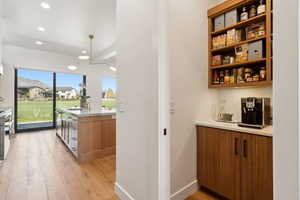 Indoor bar featuring recessed lighting, light wood-style flooring, and appliances with stainless steel finishes