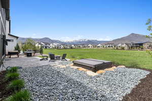View of grassy yard featuring a mountain view, a patio area, and a residential view
