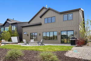 Back of property featuring board and batten siding, an outdoor fire pit, and a patio area