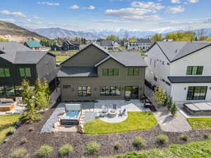 Rear view of property featuring roof with shingles, an outdoor fire pit, and a mountain view