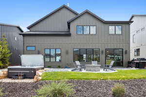 Back of property featuring a fire pit, a patio area, board and batten siding, and a hot tub