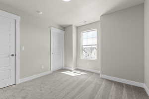 Unfurnished bedroom featuring light colored carpet and baseboards