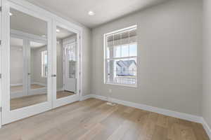Spare room featuring healthy amount of natural light, light wood-style flooring, recessed lighting, and french doors