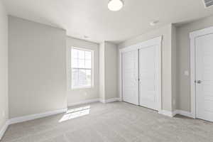 Unfurnished bedroom featuring light colored carpet and a closet