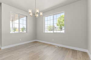 Unfurnished room featuring a chandelier and light wood-style floors