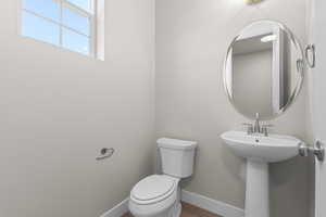 Half bathroom with toilet and baseboards