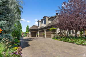 View of side of property with stone & stucco siding, heated driveway, and oversized garage