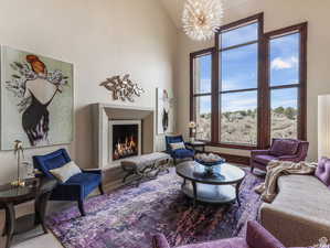 Living room with a lit fireplace, high vaulted ceiling, and a chandelier