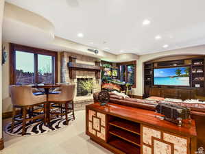 Living area featuring a stone fireplace, baseboards, recessed lighting, and carpet