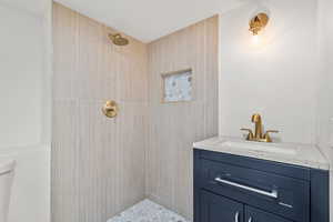Full bath with tiled shower, toilet, and vanity