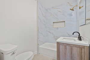 Full bathroom with tile patterned floors, toilet, vanity, baseboards, and tub / shower combination