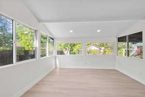 Unfurnished sunroom featuring healthy amount of natural light, wood finished floors, recessed lighting, and baseboards