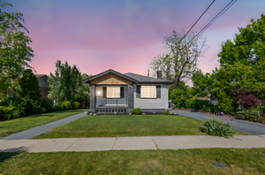 Bungalow-style home featuring a lawn, a chimney, and a porch