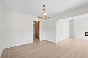 Spare room featuring arched walkways, light wood-type flooring, and baseboards