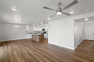 Unfurnished living room featuring dark wood-style floors, a chandelier, a textured ceiling, and a ceiling fan