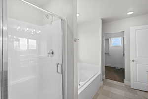 Full bathroom with a bath, a stall shower, and light tile patterned floors