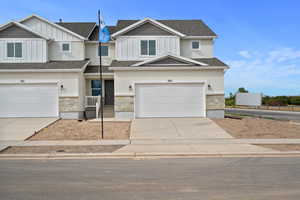 Craftsman house featuring board and batten siding, stone siding, driveway, and a shingled roof