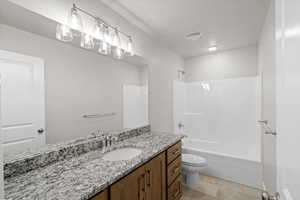 Bathroom with vanity, washtub / shower combination, a textured ceiling, and light tile patterned flooring