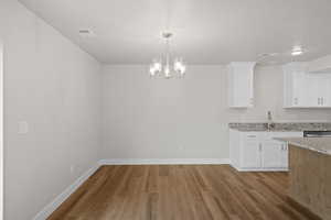 Unfurnished dining area with a chandelier and light wood-style flooring