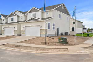 View of front of house featuring board and batten siding, concrete driveway, stone siding, a residential view, and a garage