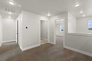 Hall with dark colored carpet, a textured ceiling, and recessed lighting