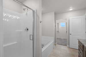 Full bathroom featuring vanity, a garden tub, a shower stall, and light tile patterned floors