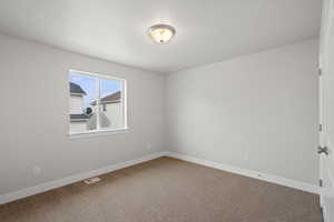 Spare room featuring baseboards and carpet