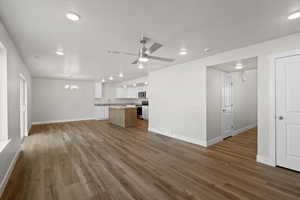 Unfurnished living room featuring a chandelier, dark wood-type flooring, recessed lighting, and a ceiling fan