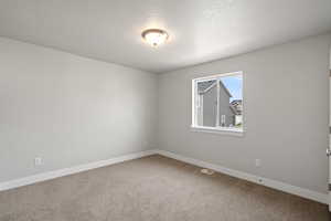 Empty room featuring light carpet and a textured ceiling