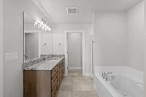 Full bath featuring vanity, a garden tub, and a textured ceiling