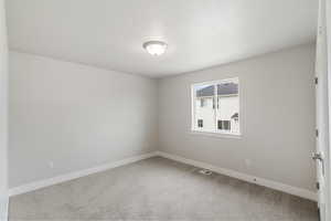 Unfurnished room with light carpet and a textured ceiling