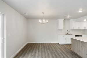Kitchen with white cabinets, a chandelier, decorative light fixtures, and dark wood-type flooring
