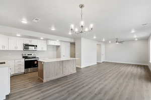 Kitchen featuring stainless steel appliances, decorative light fixtures, ceiling fan, white cabinets, and recessed lighting