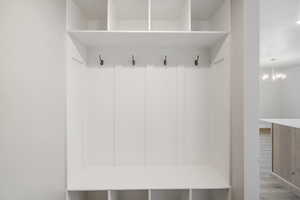 Mudroom with a textured ceiling, a chandelier, and wood finished floors