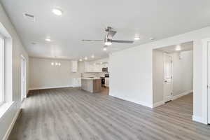 Unfurnished living room featuring light wood-style floors, a chandelier, ceiling fan, and recessed lighting