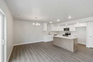 Kitchen featuring a chandelier, white cabinetry, appliances with stainless steel finishes, pendant lighting, and a center island