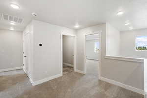 Empty room with light colored carpet, recessed lighting, and a textured ceiling