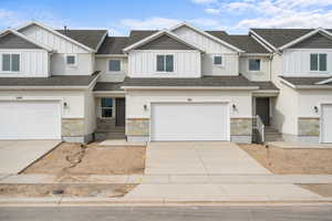 Craftsman house with board and batten siding, stone siding, concrete driveway, and roof with shingles