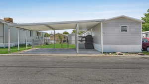 View of parking with fence, a carport, driveway, and a gate