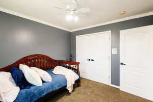 Carpeted bedroom featuring ornamental molding, a closet, ceiling fan, and baseboards